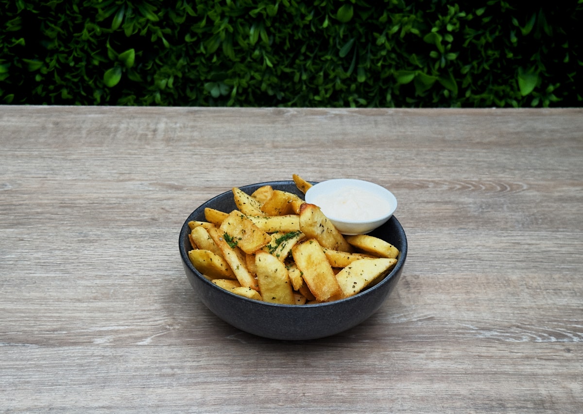 A bowl of french fries on a wooden table